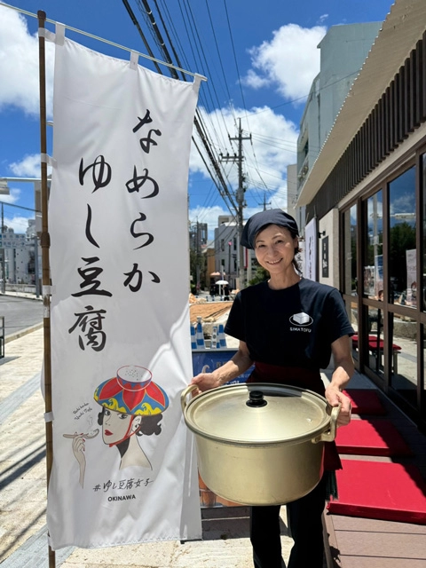 「なめらかゆし豆腐」のぼりの前に立つ玉寄文子