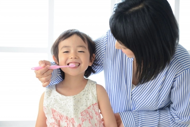 母親に歯磨きをしてもらう女の子