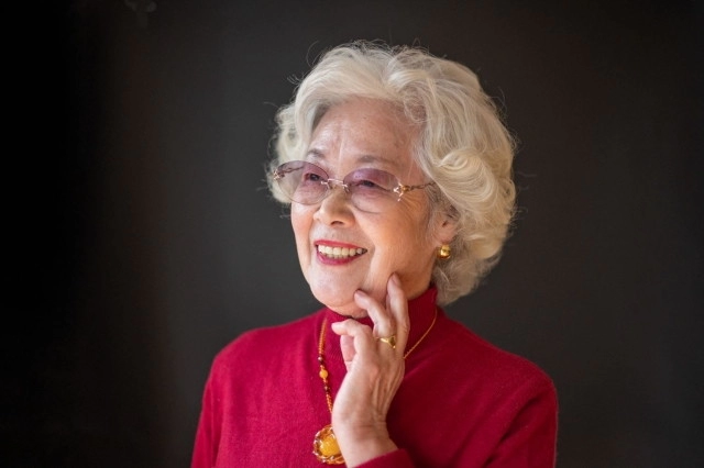 顔に手を当てる笑顔のマダム