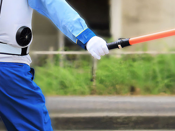 道路で誘導棒を振る警備スタッフ