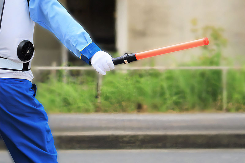 交通整理のため警棒を持つ警備員の腕