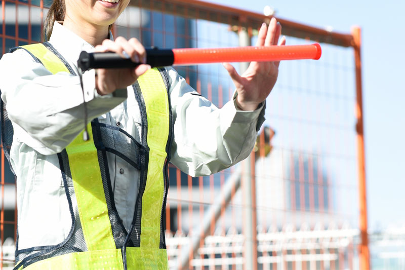 工事現場で誘導棒を持つ女性警備員