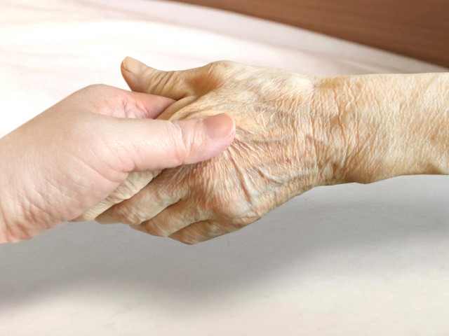 若い手が高齢者の手を優しく握っている様子