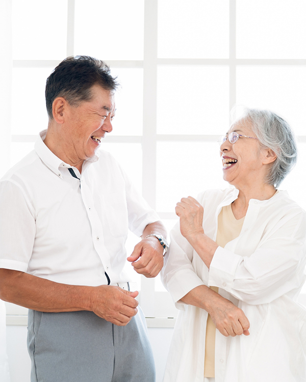 高齢の夫婦が明るい部屋で楽しそうに笑い合っている様子