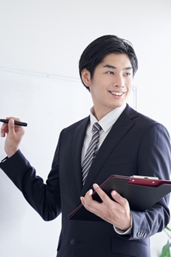 スーツ姿の男性がホワイトボードを使ってプレゼンテーションをしている様子