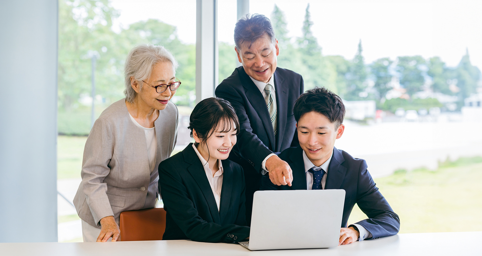 若いビジネスマンが高齢者の夫婦にタブレットを使って説明している様子