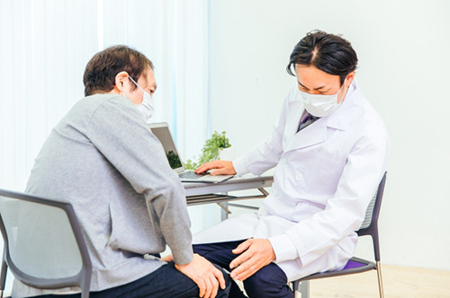 患者の足の診察をする男性医師