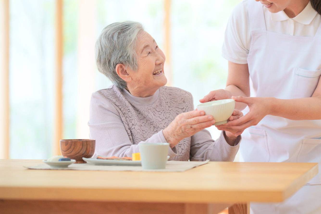 笑顔でお椀を受け取る高齢の女性