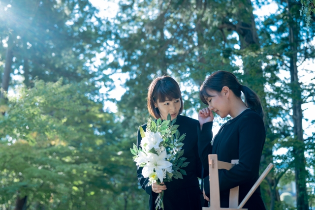 和室で棺に花を納める納棺師の女性の様子