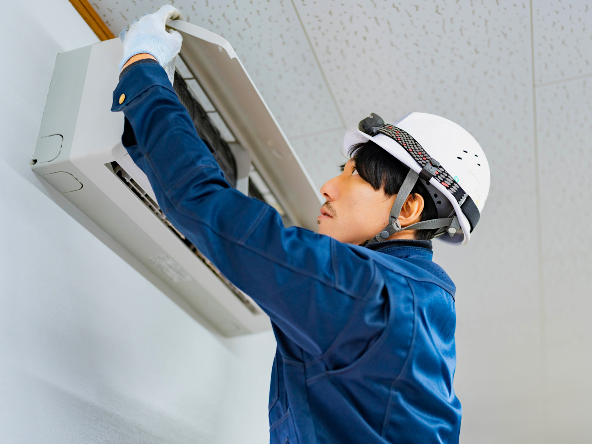 室内でエアコンを取り付ける作業員