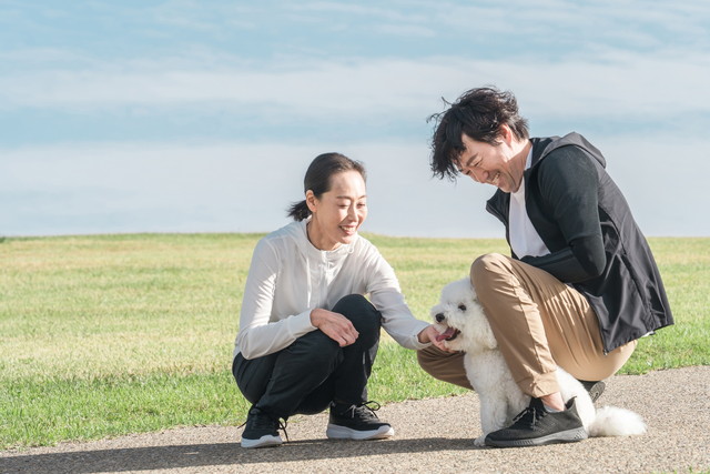 屋外で犬と触れ合い笑顔を見せる夫婦