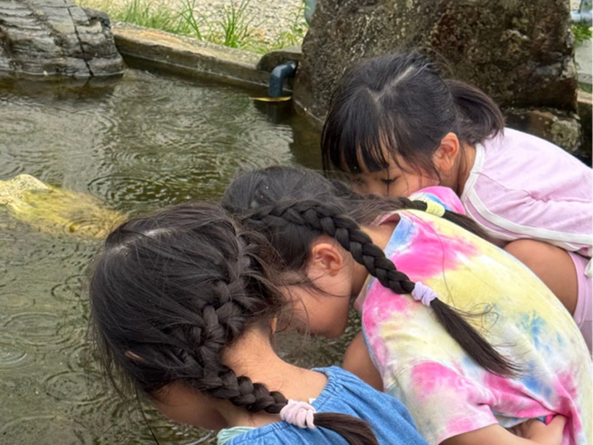 池をのぞきこむ子どもたち