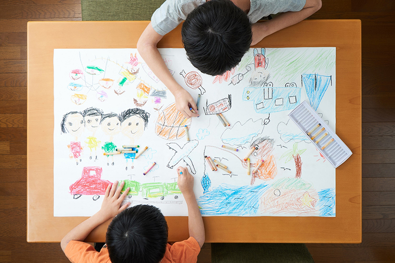 雨上がりの園庭で観察する子ども