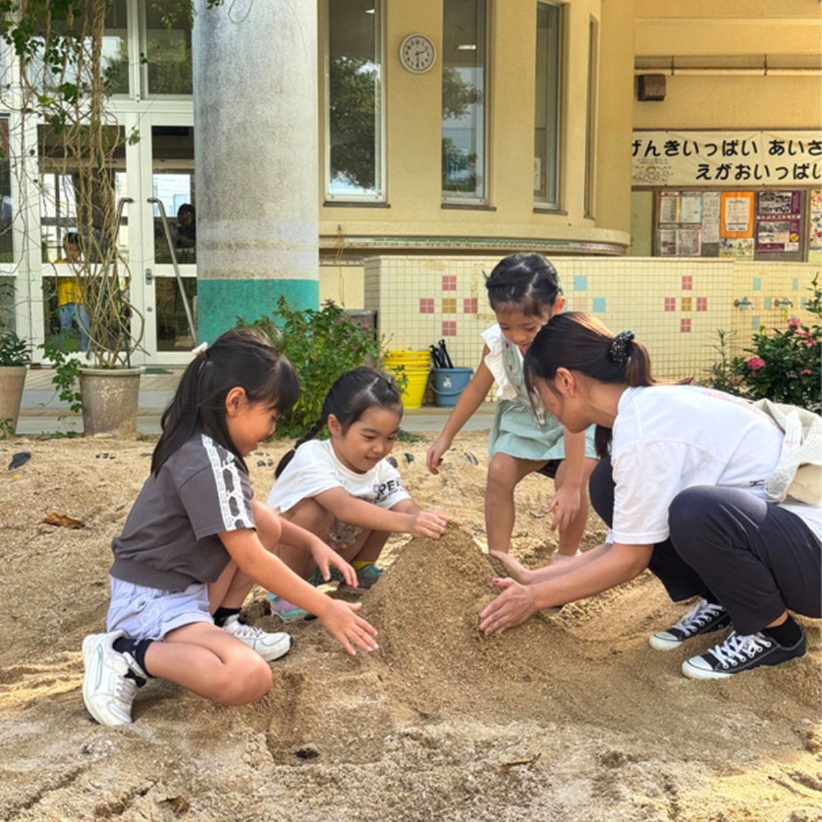 砂場で子どもと遊ぶ職員