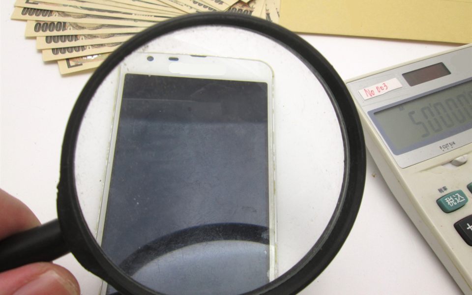虫眼鏡でスマートフォンを確認する査定のイメージ