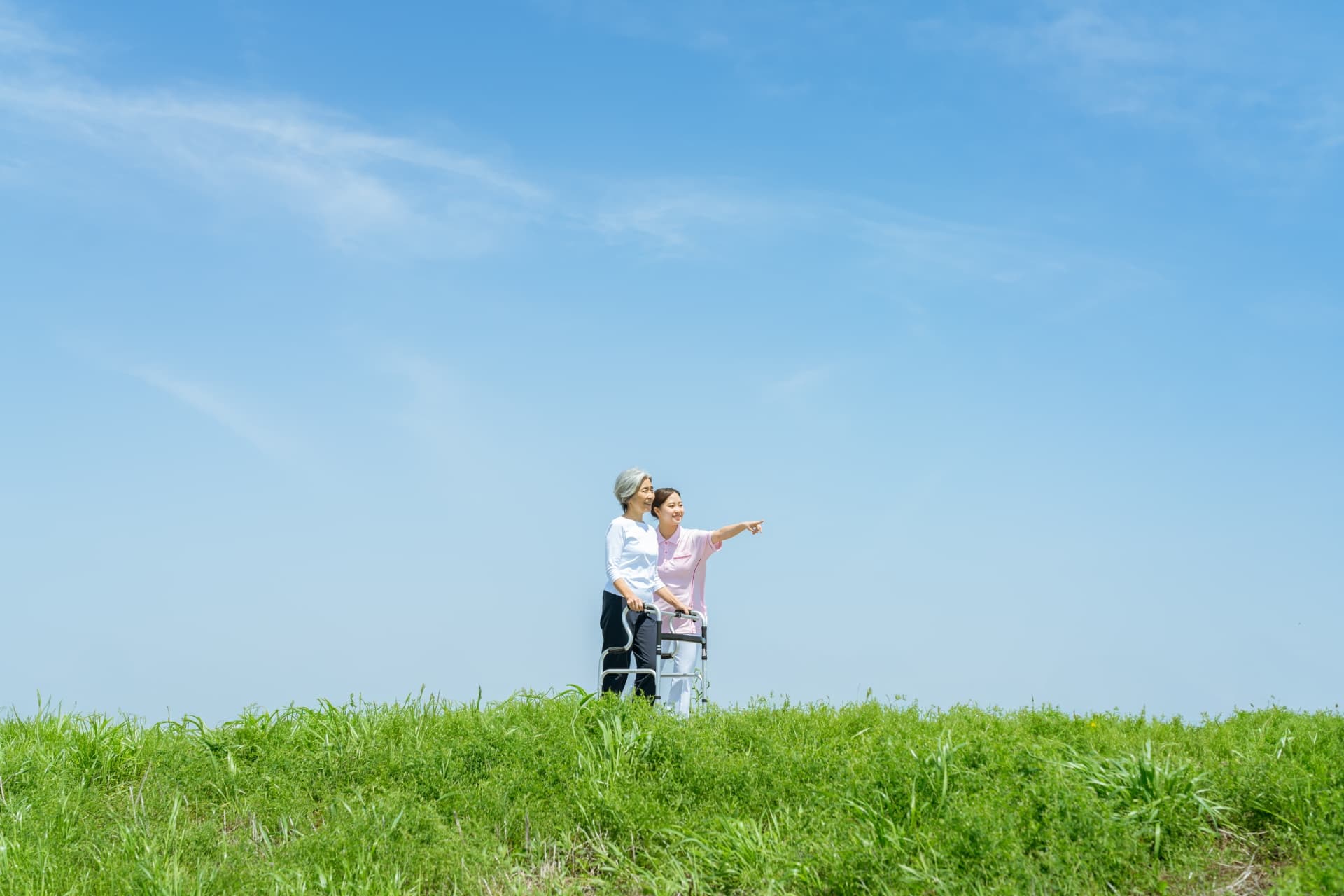 介助者と利用者が草原を一緒に歩く様子