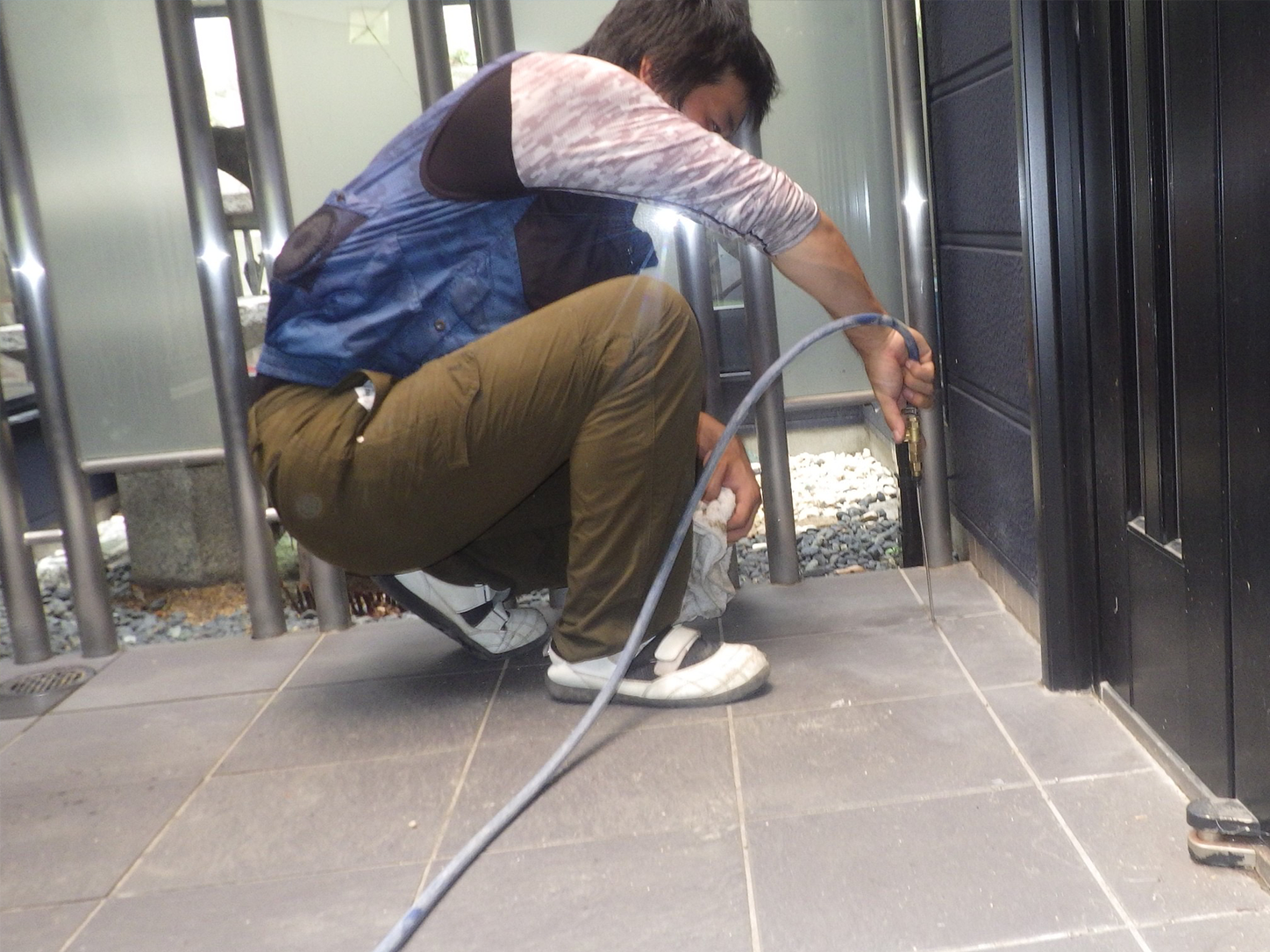 防護服を着て住宅の軒下に薬剤を散布する作業スタッフ