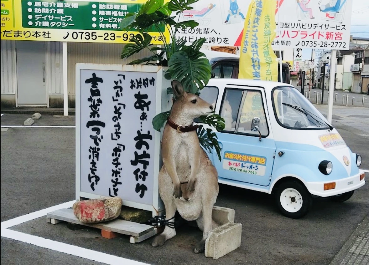 看板と車両のそばに立つカンガルーの置物