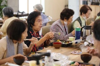 テーブルを囲んで一緒にお食事を楽しむてぃーらの利用者さま