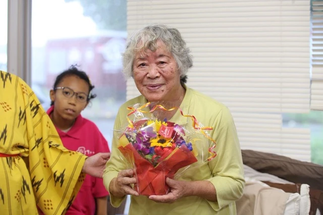 トーカチ祝いでお祝いの花を持つ利用者さま